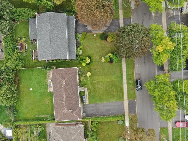 Straight-down aerial photograph of houses, lawns, driveways and a street.